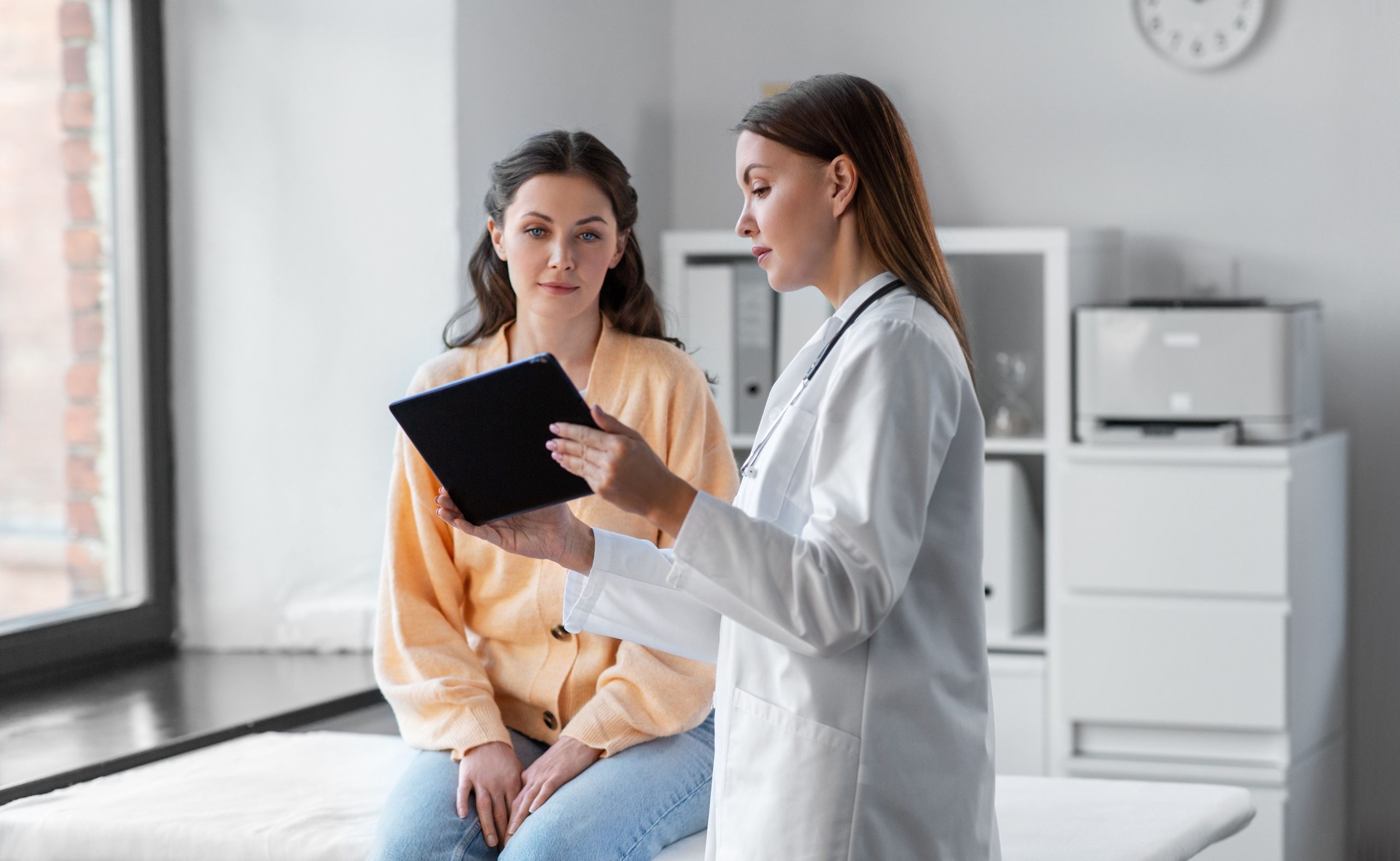 woman and doctor in doctors office with tablet