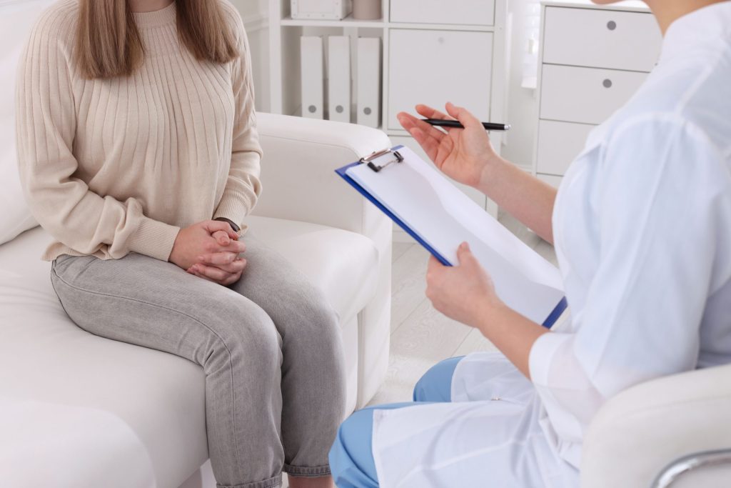 Woman in doctors office with doctor taking notes on clip board